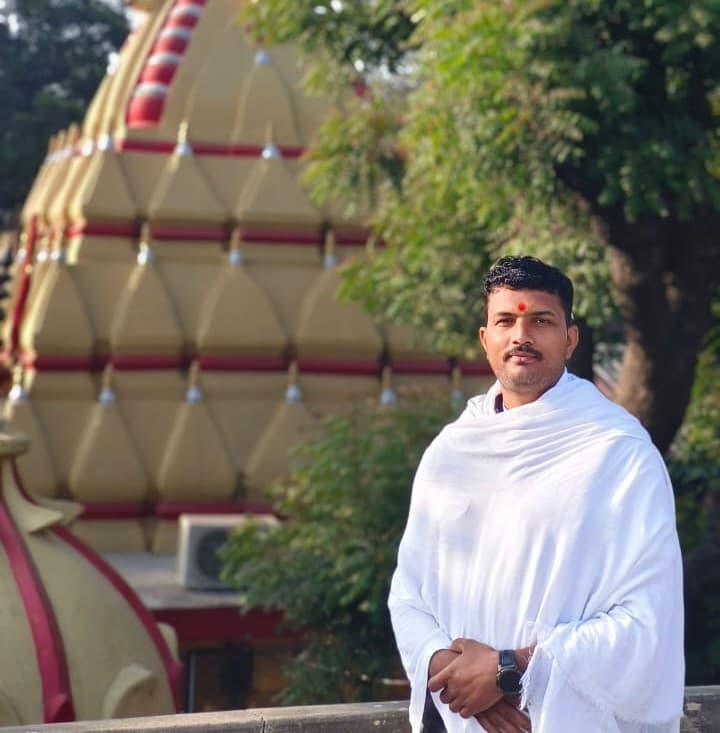 A man in traditional attire standing in front of a temple